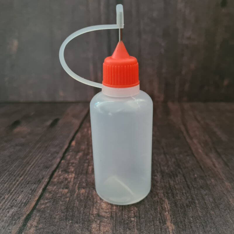 Small plastic dye applicator bottle with fine applicator nozzle and fastening tip