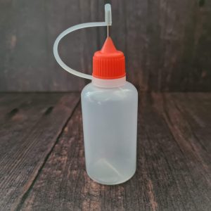 Small plastic dye applicator bottle with fine applicator nozzle and fastening tip