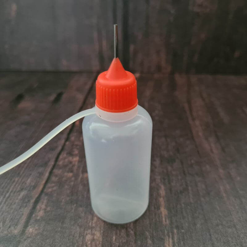 Small plastic dye applicator bottle with fine applicator tip and fastening tip
